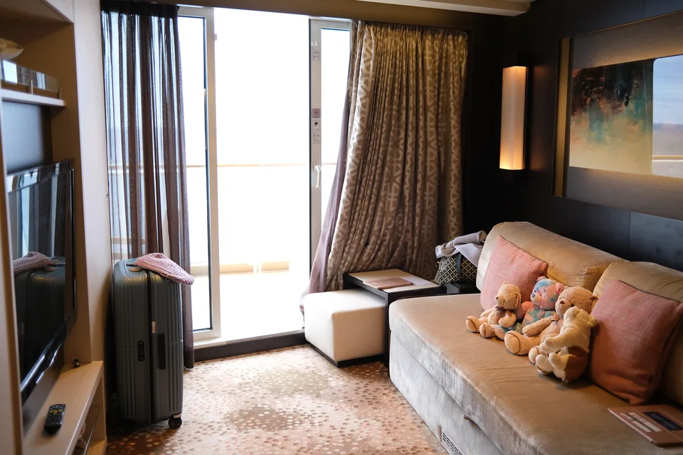 Stuen i Haven-suite 13906 på Norwegian Escape med sofa, bamser og skydedør ud til terrassen