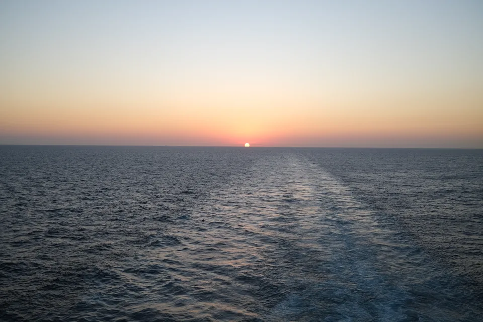 Solnedgang over havet set agterud over kølvandet fra Norwegian Escape