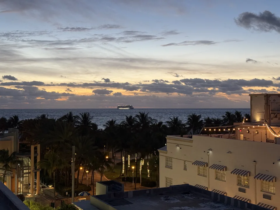 Daggry over Atlanterhavet fra South Beach i Miami med palmer, art deco-hotel og et krydstogtskib i horisonten