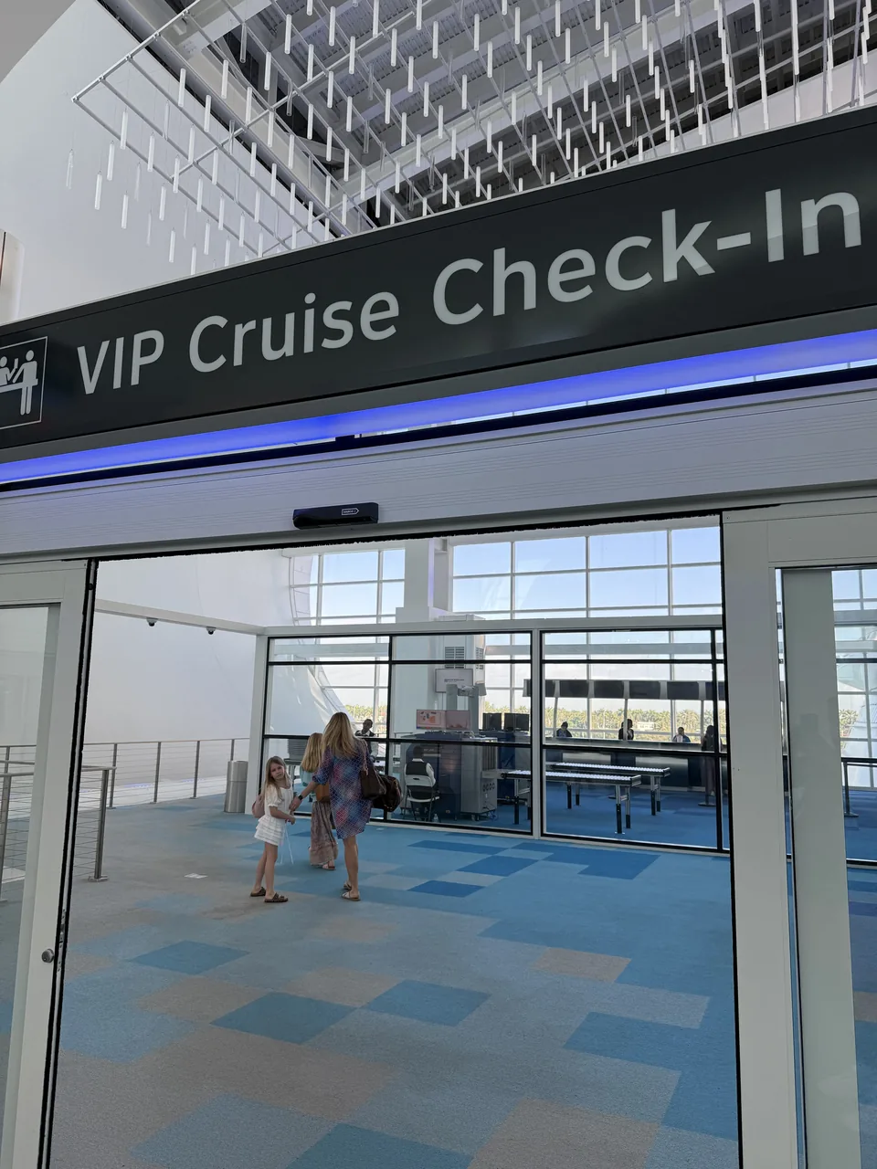 VIP Cruise Check-In i PortMiami med lys hal, blåt tæppe og glasfacade før ombordstigning på Norwegian Escape