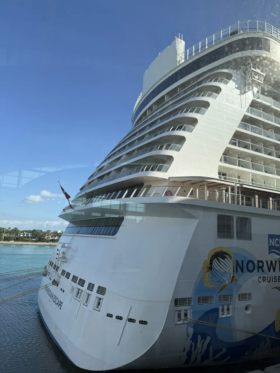 Agterenden af Norwegian Escape ved kajen i PortMiami med skibets navn og de trappede agterbalkoner