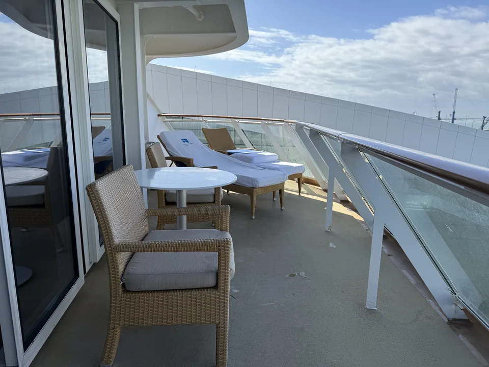 Terrassen på Haven-suite 13906 med flettede stole, rundt bord og to liggestole på Norwegian Escape