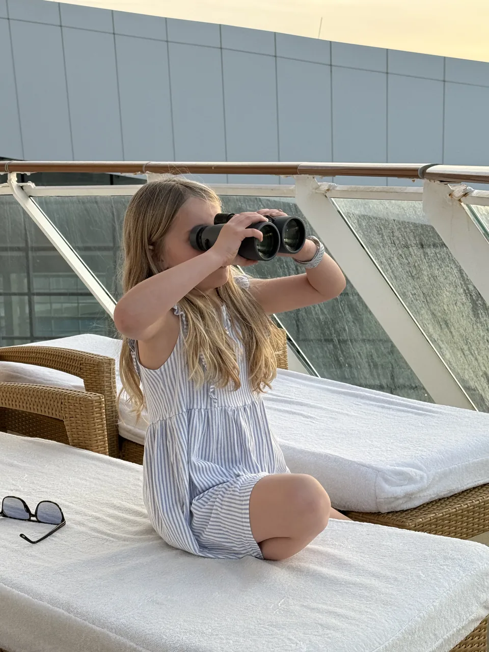 Barn med kikkert på liggestolen på Haven-terrassen under sailaway fra PortMiami på Norwegian Escape