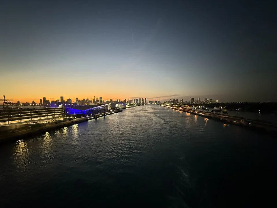 Skumring over havnekanalen ud af PortMiami med Miamis skyline og blåt oplyste terminaler