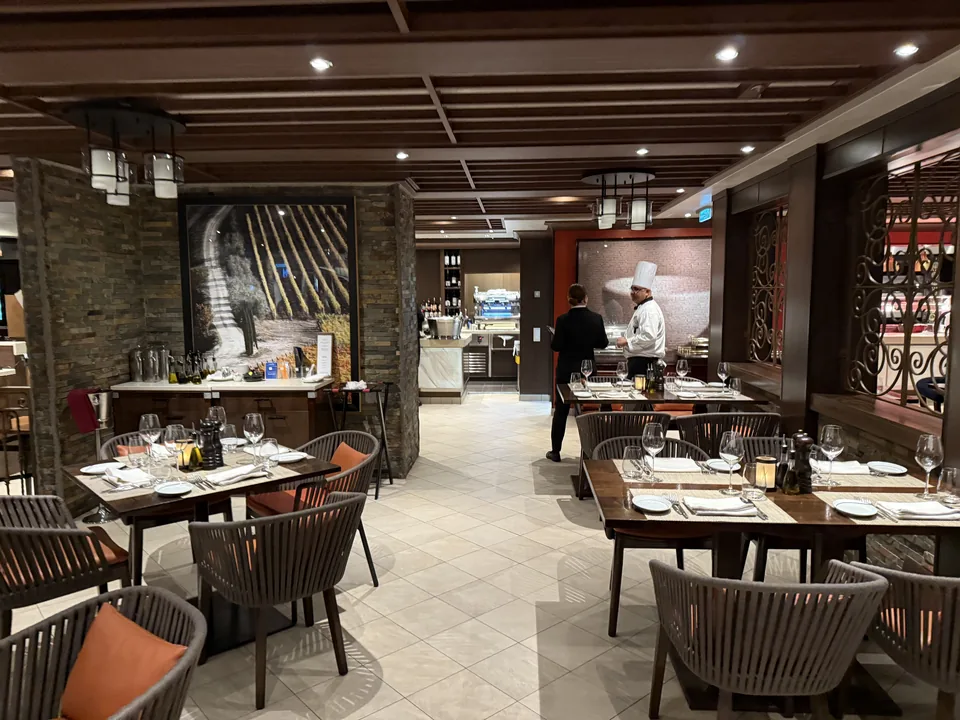 Spisesalen på La Cucina med dækkede borde og åbent køkken på Norwegian Escape