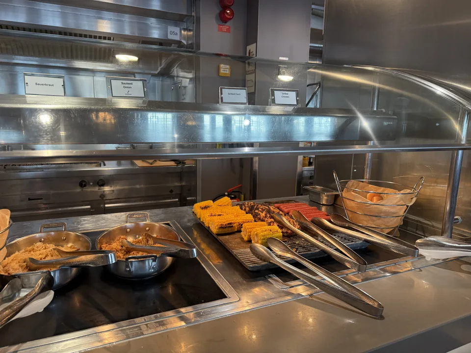 Grillstation med majskolber, grillet kylling og pølser på buffeten i Garden Café på Norwegian Escape