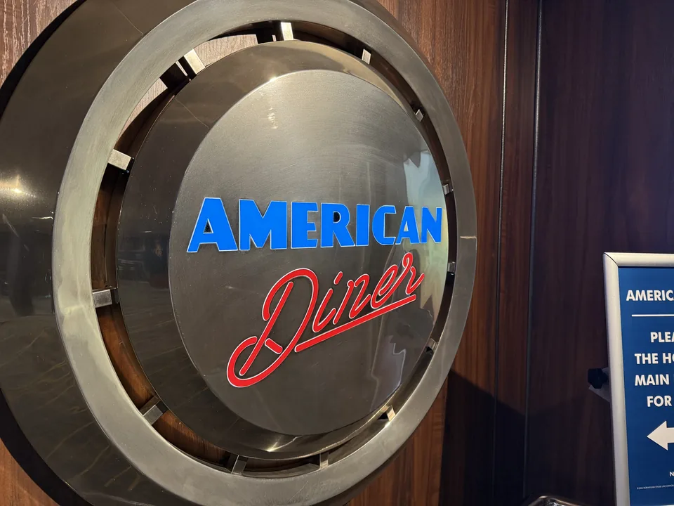 Det runde metalskilt ved indgangen til restauranten American Diner på Norwegian Escape