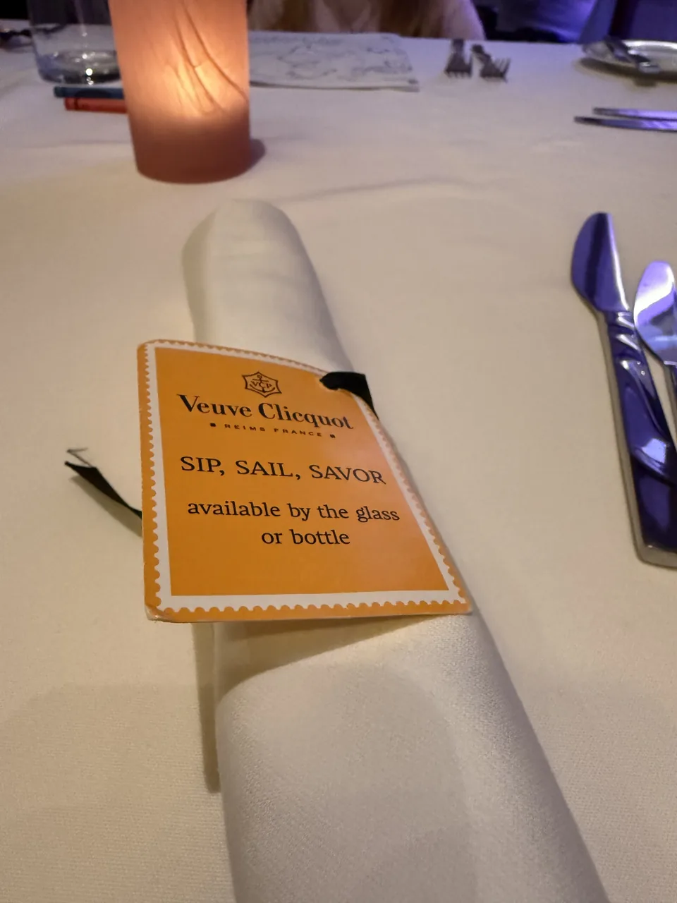Serviet med Veuve Clicquot-kort på det dækkede bord på Le Bistro på Norwegian Escape