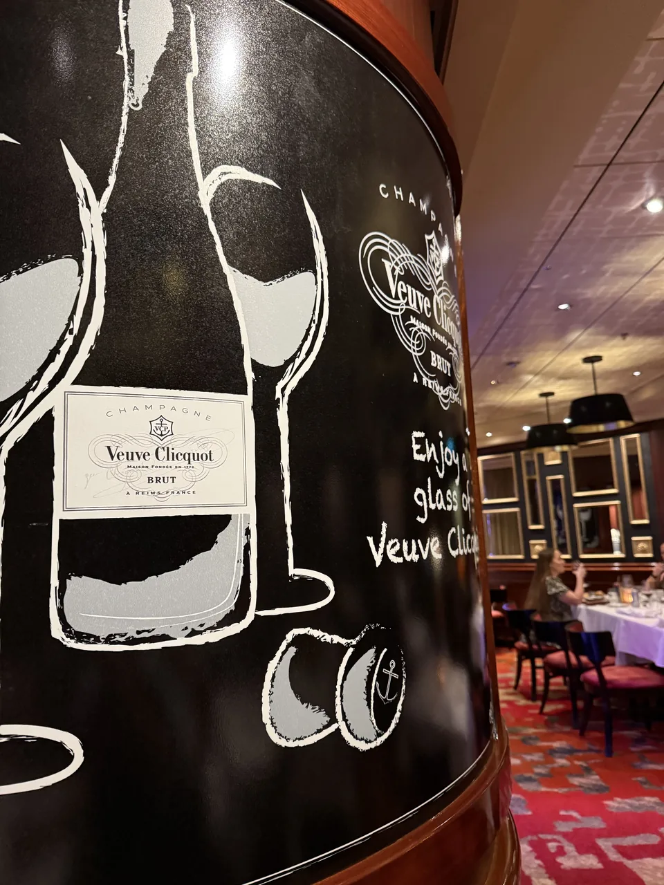 Veuve Clicquot-tavle ved indgangen til den franske restaurant Le Bistro på Norwegian Escape