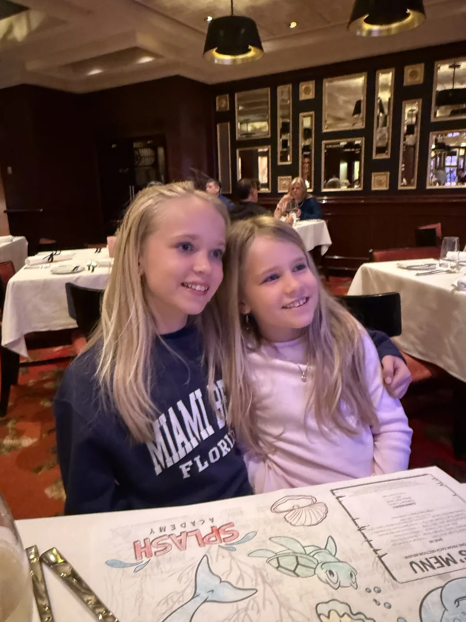 To piger ved bordet på Le Bistro med tegneark fra Splash Academy på Norwegian Escape