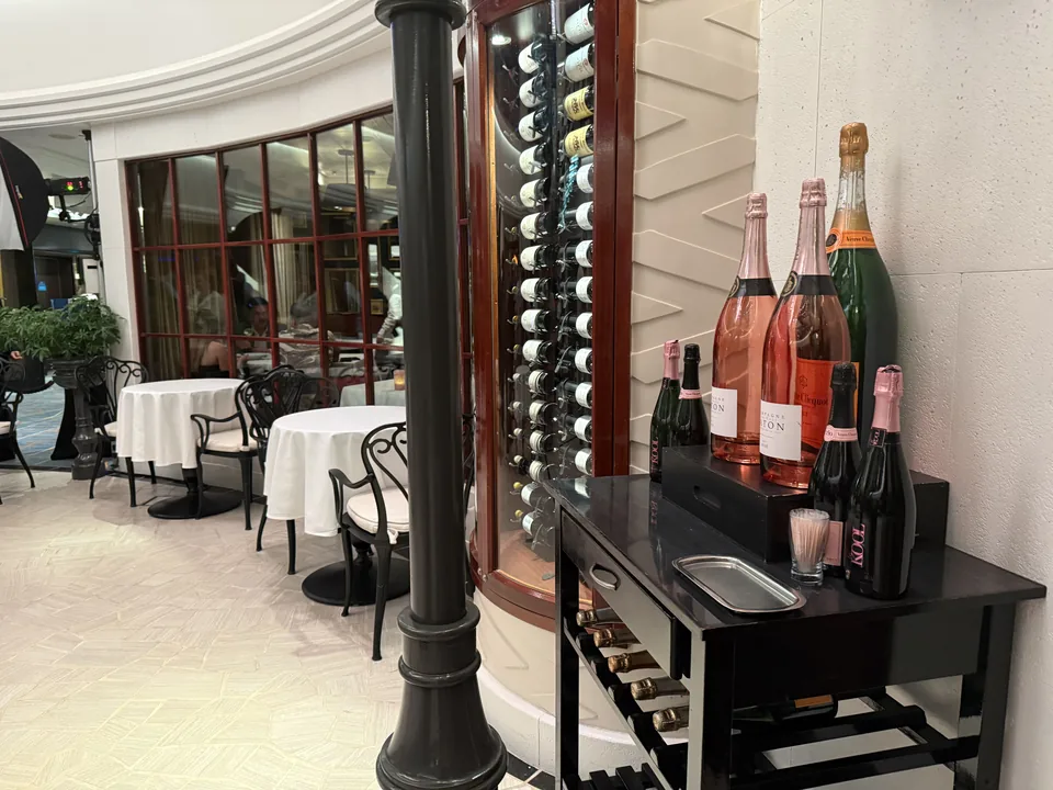 Vinvæg og champagneudstilling ved indgangen til Le Bistro på Norwegian Escape