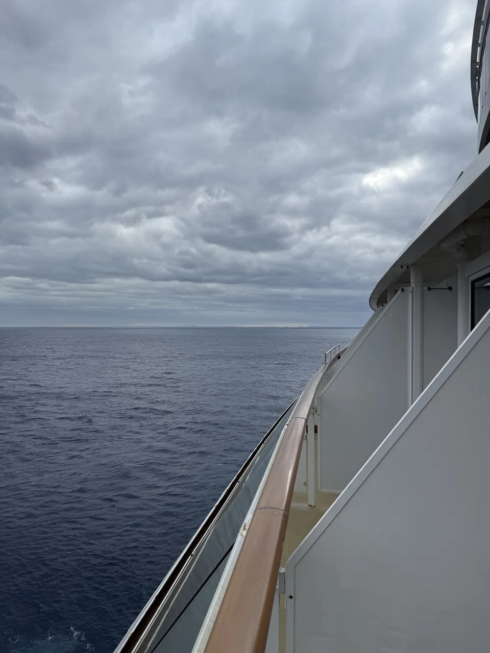 Mørkeblåt hav og gråt skydække set langs skibssiden på Norwegian Escape på havdagen mod Cozumel