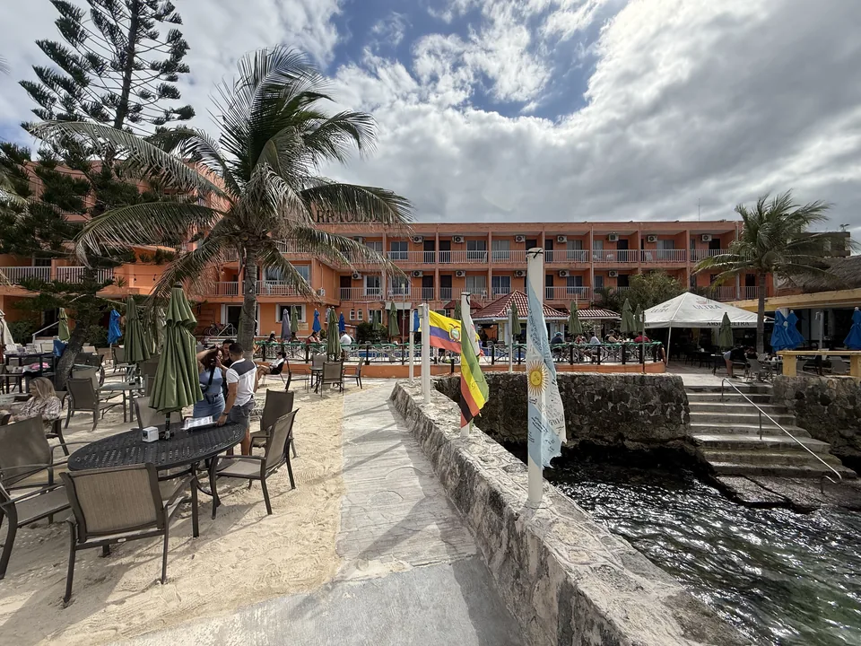 Strandbar med grønne parasoller og orange hotel ved vandkanten på Cozumel nær krydstogtmolen