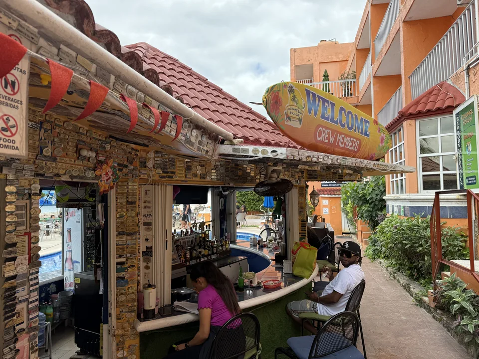 Poolbar med surfbrætskiltet Welcome Crew Members ved et orange hotel på Cozumel