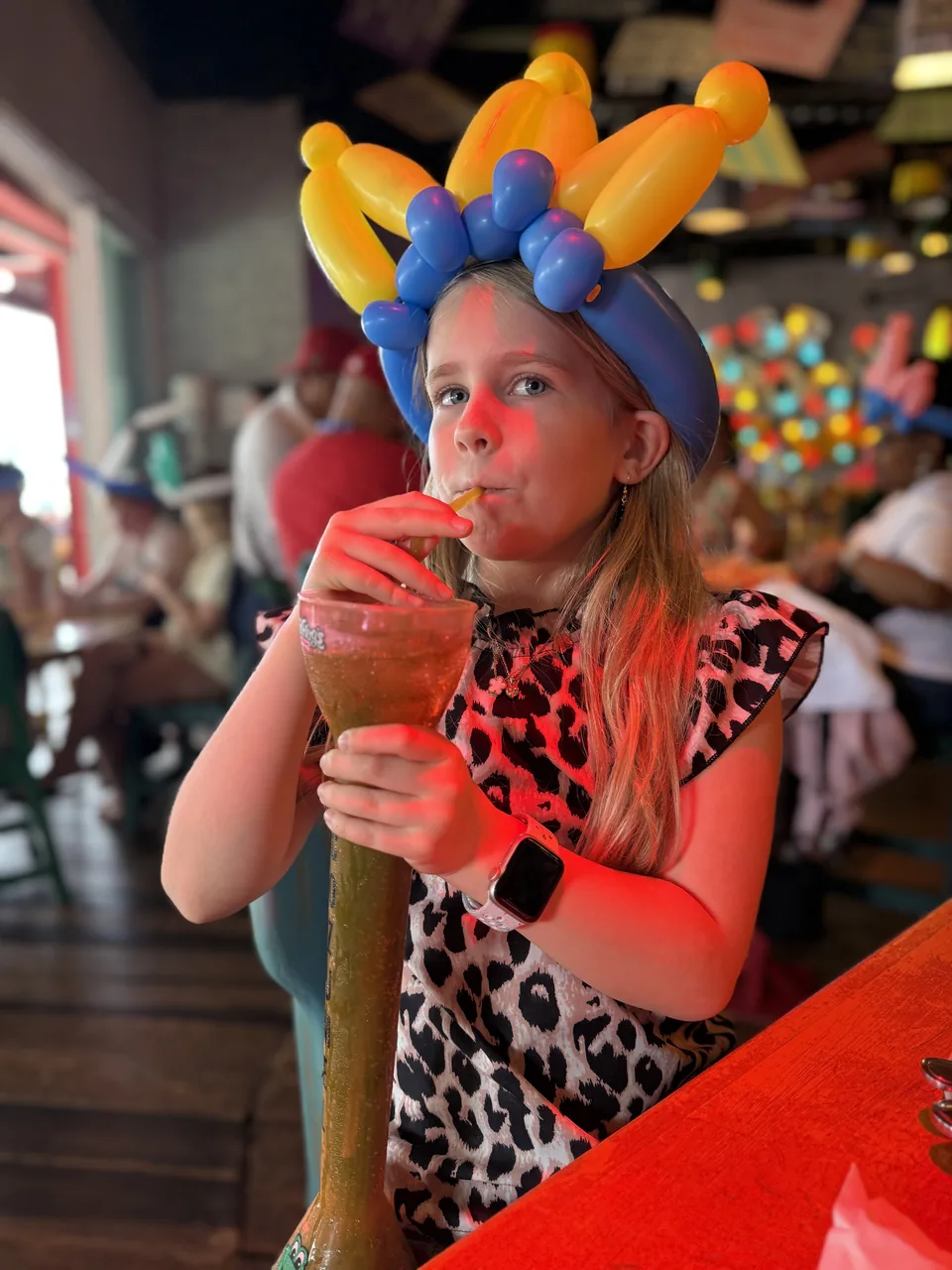 Pige med ballonkrone drikker af et højt yard-glas i den festlige bar Señor Frog's på Cozumel