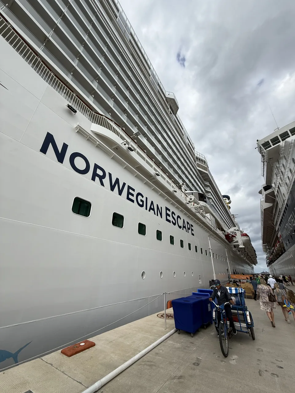 Vidvinkel af skibssiden med navnet Norwegian Escape i store bogstaver ved molen på Cozumel