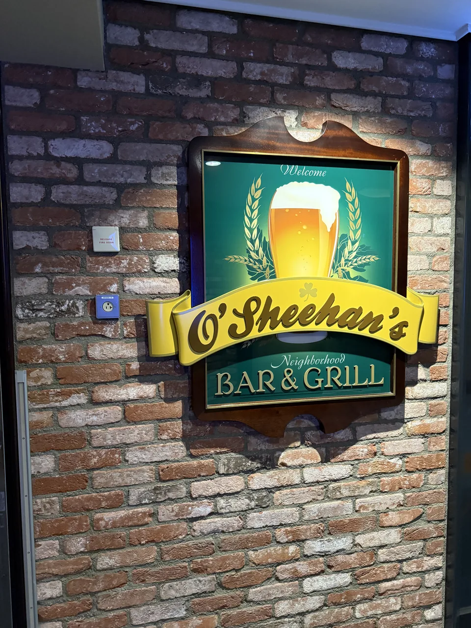 Skiltet ved O'Sheehan's Neighborhood Bar & Grill på en murstensvæg om bord på Norwegian Escape
