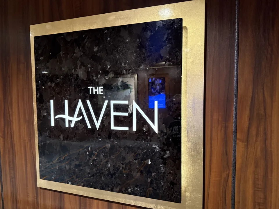 Det oplyste skilt ved indgangen til The Haven på Norwegian Escape i sort sten og guldramme