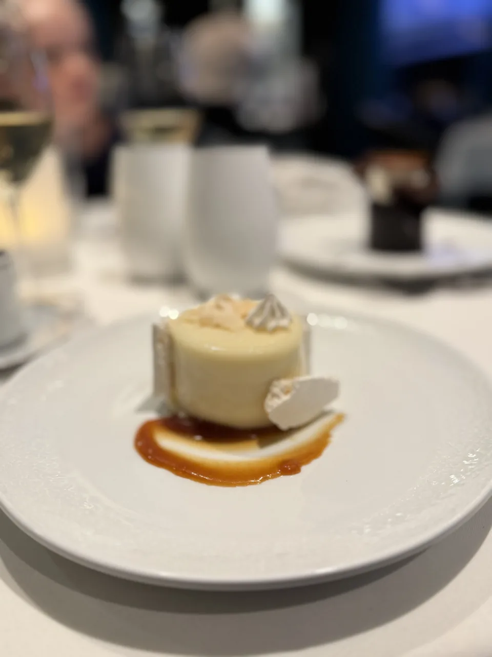Dessert med lys, cremet kage, karamelsauce og marengsflager i Restaurant Haven på Norwegian Escape