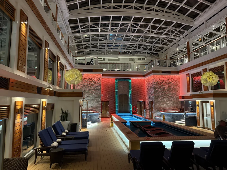 Haven Courtyard med pool og boblebade under glastaget om aftenen på Norwegian Escape