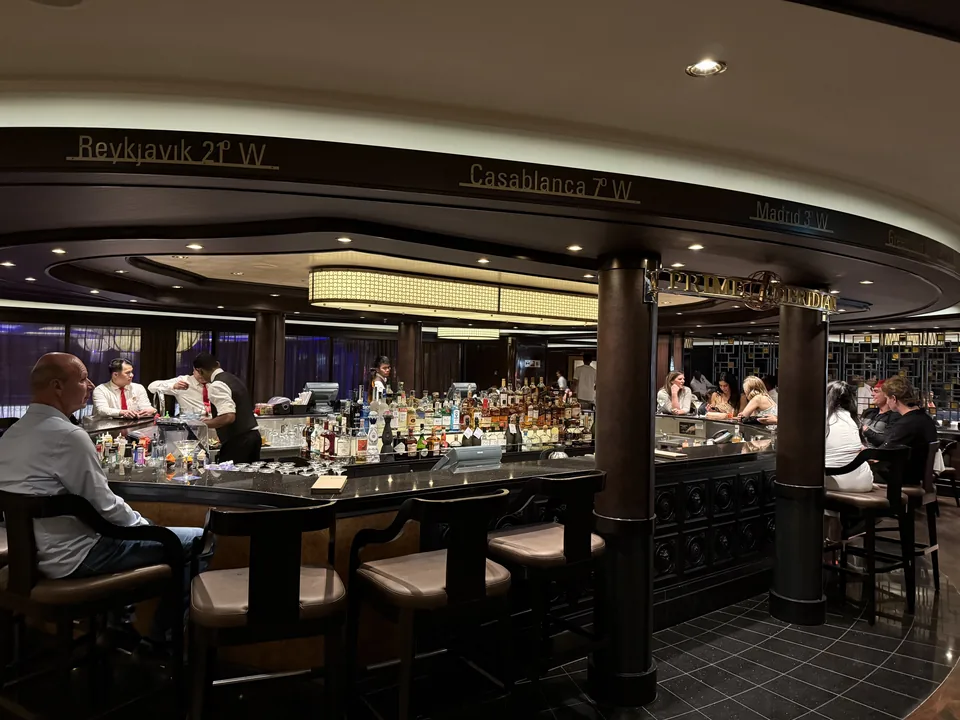 Prime Meridian Bar på Norwegian Escape med rund bardisk og loftskant med byer og længdegrader