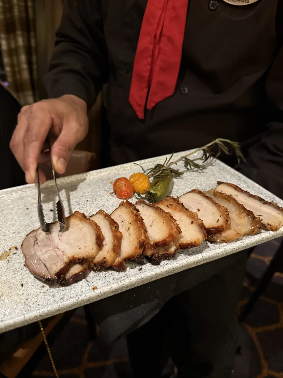 Passador serverer skiver af stegt svinekød med tang ved bordet på Moderno Churrascaria