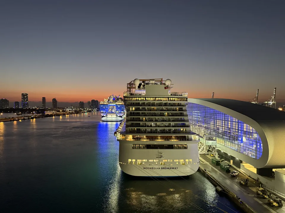 Daggry over PortMiami med Norwegian Breakaway ved kajen og Miamis skyline set fra Norwegian Escape