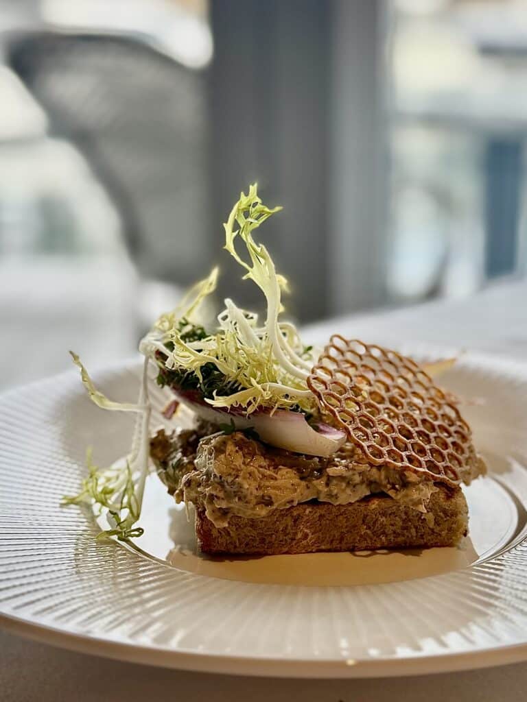 Restaurant Address Hellerup en smuk open-faced sandwich med sprøde elementer og friske urter.