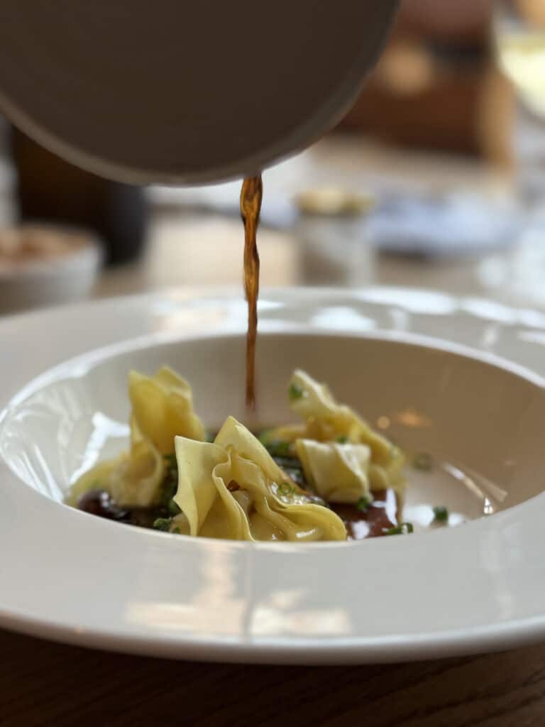Chateau Forêt anmeldelse bistro Helsinborg, gule ravioli serveret i hvid skål med sauce.