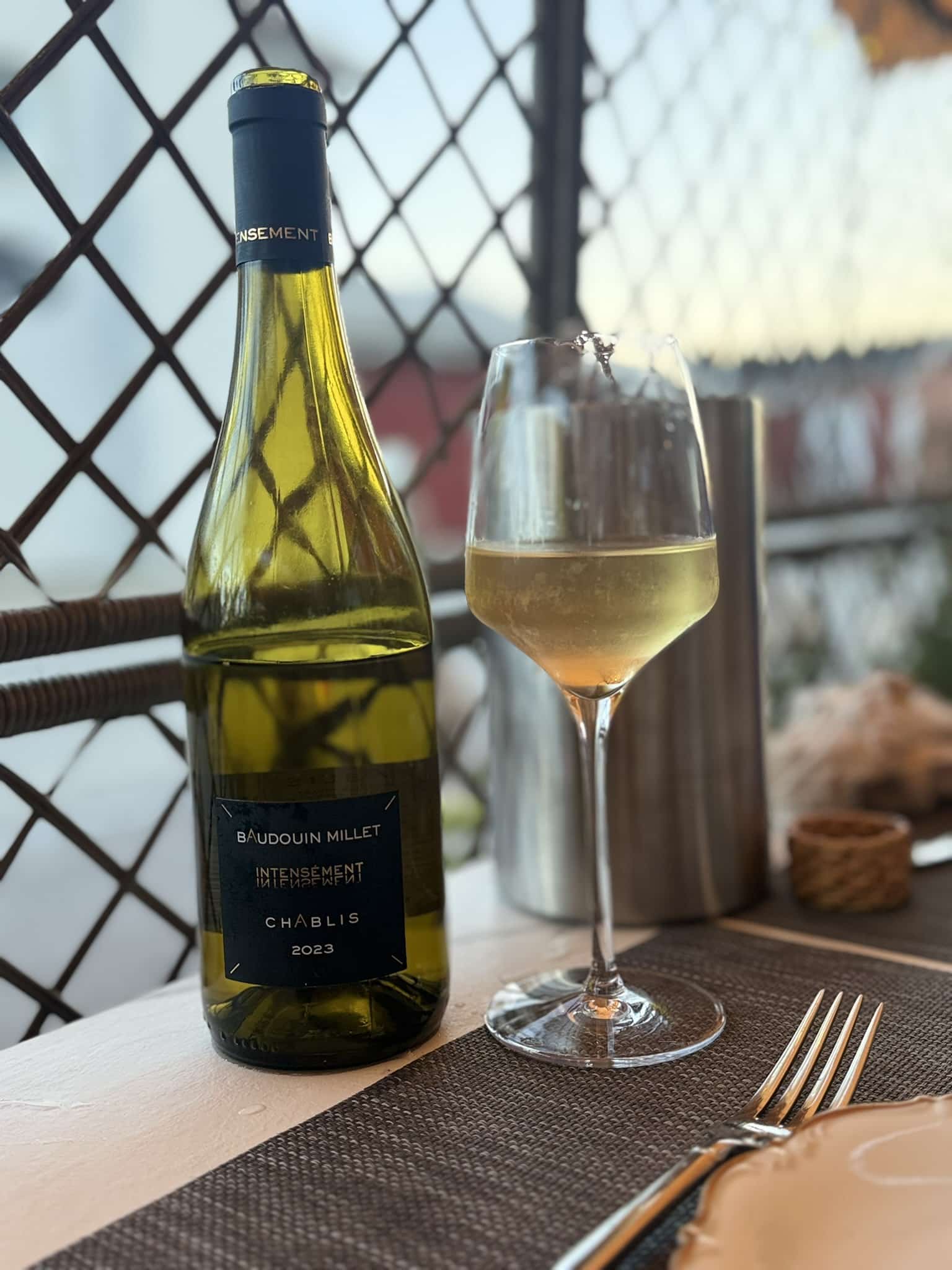 Flaske Baudouin Millet Chablis 2023 ved siden af fyldt hvidvinsglas