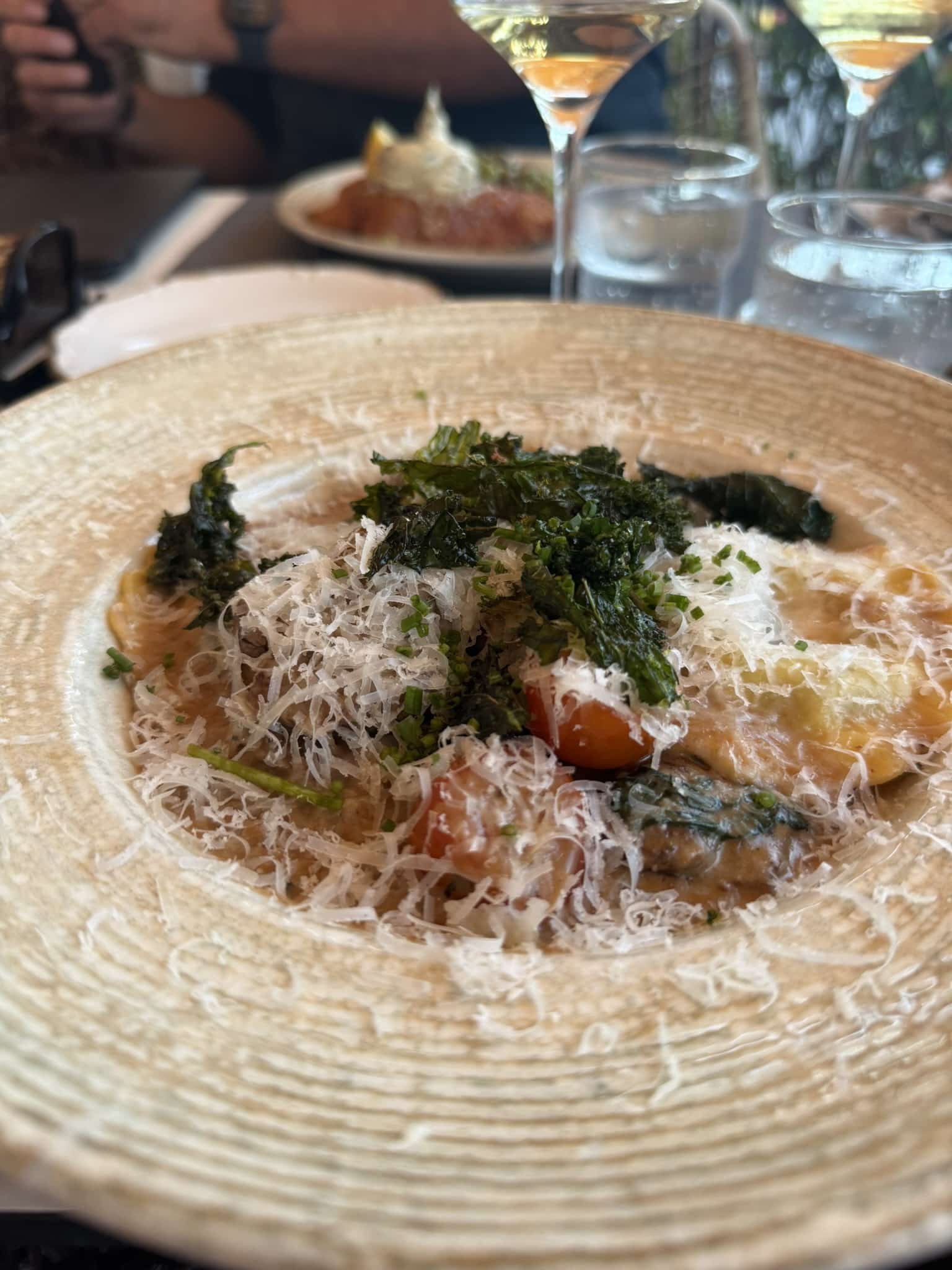 Ravioli med tomater, sprød grønkål og revet parmesan i dyb skål