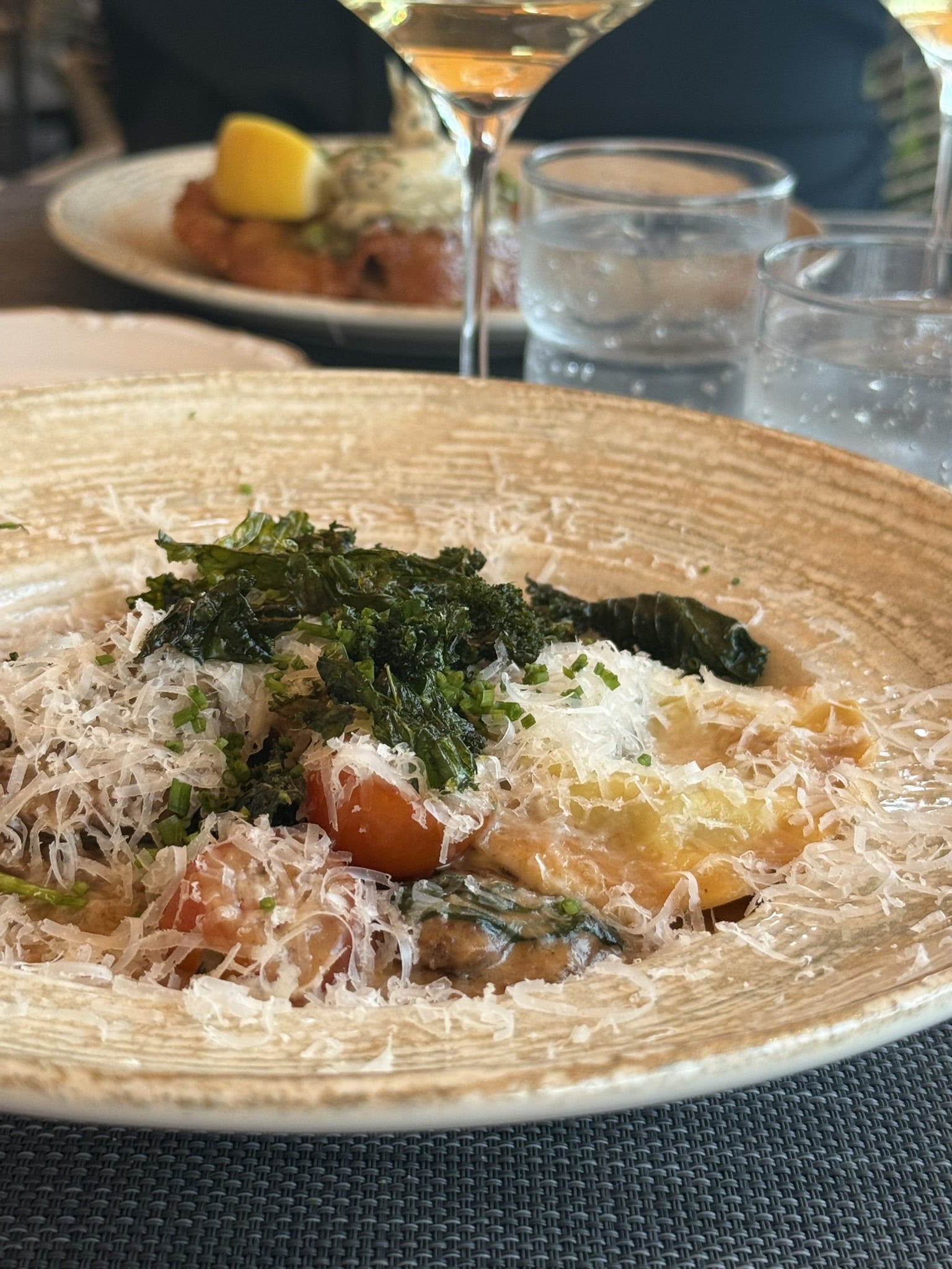 Ravioli med revet parmesan, sprød grønkål, cherrytomater og purløg i dyb skål