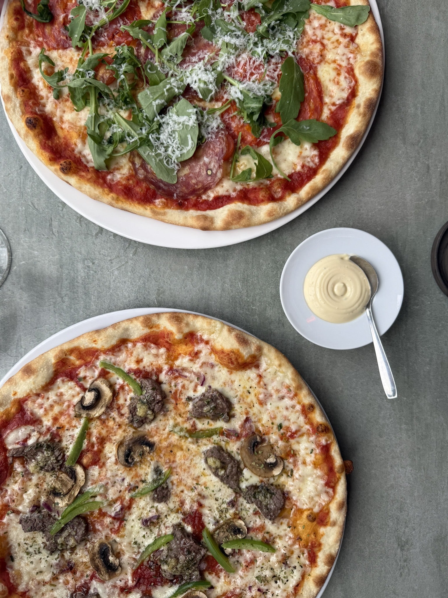 To pizzaer set fra oven, én med salami og rucola, én med kød og champignon