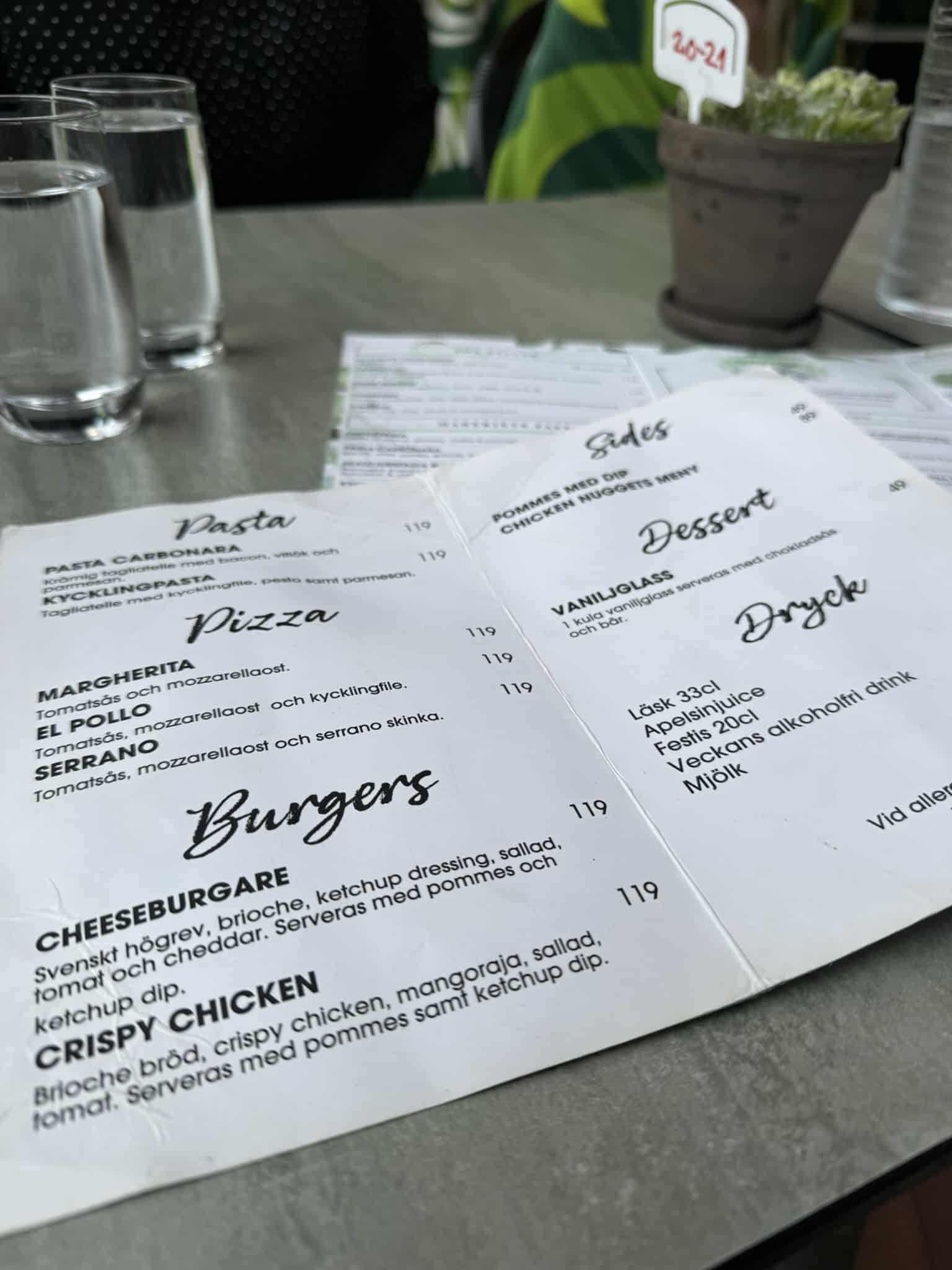 Børnemenu med pasta, pizza, burgere, dessert og drikke på bordet.
