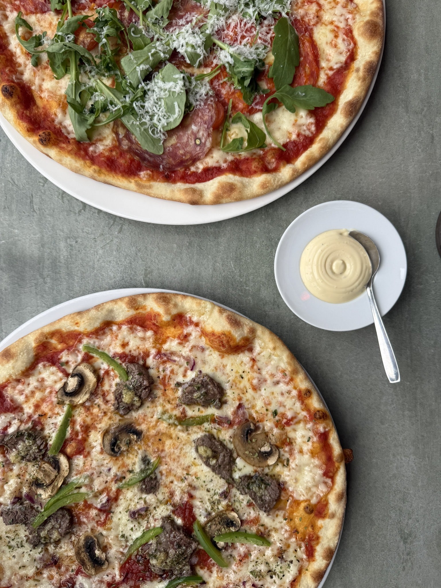 To pizzaer set fra oven med salami, rucola samt oksekød og champignon