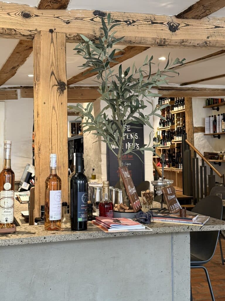 Bardisk i terrazzo med vinflasker, oliventræ, bjælker og vinreoler i baggrunden