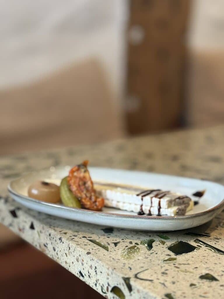 Skivet hvid ost med balsamico, syltet agurk, løg og tørret tomat