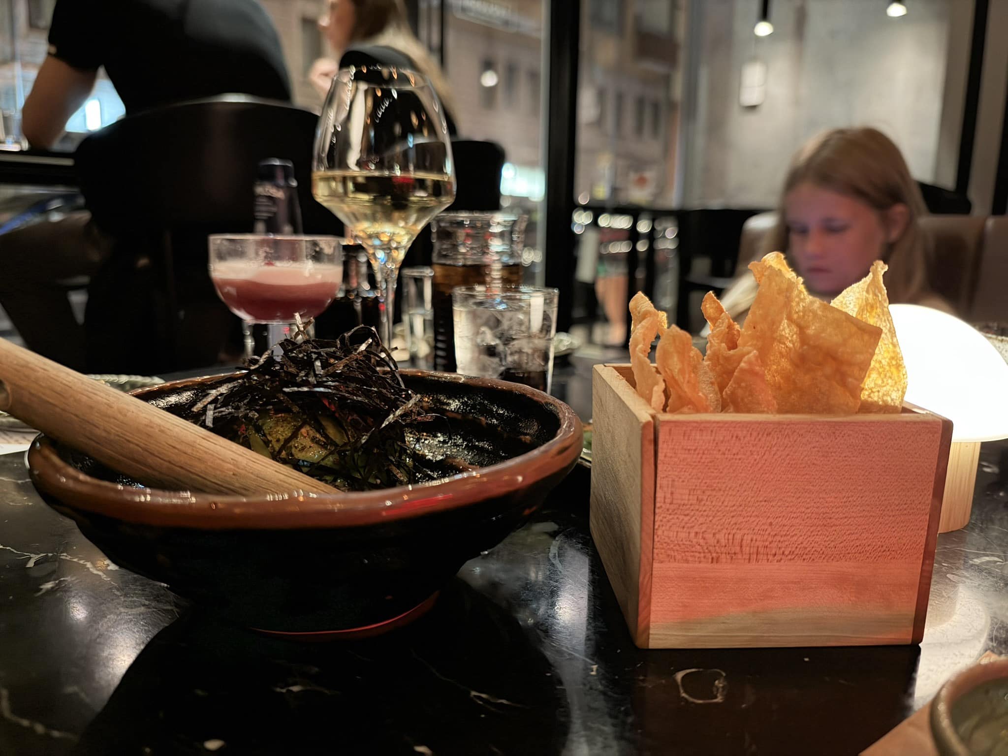 Guacamash i morter med nori og sprøde chips i trækasse.