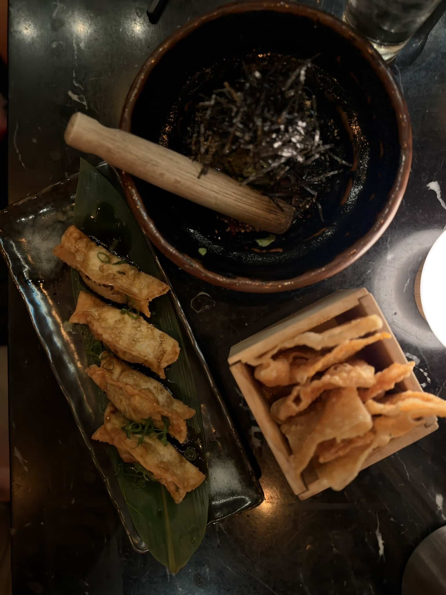 Friturestegte gyoza på bananblad, morter med nori og træboks med sprøde chips