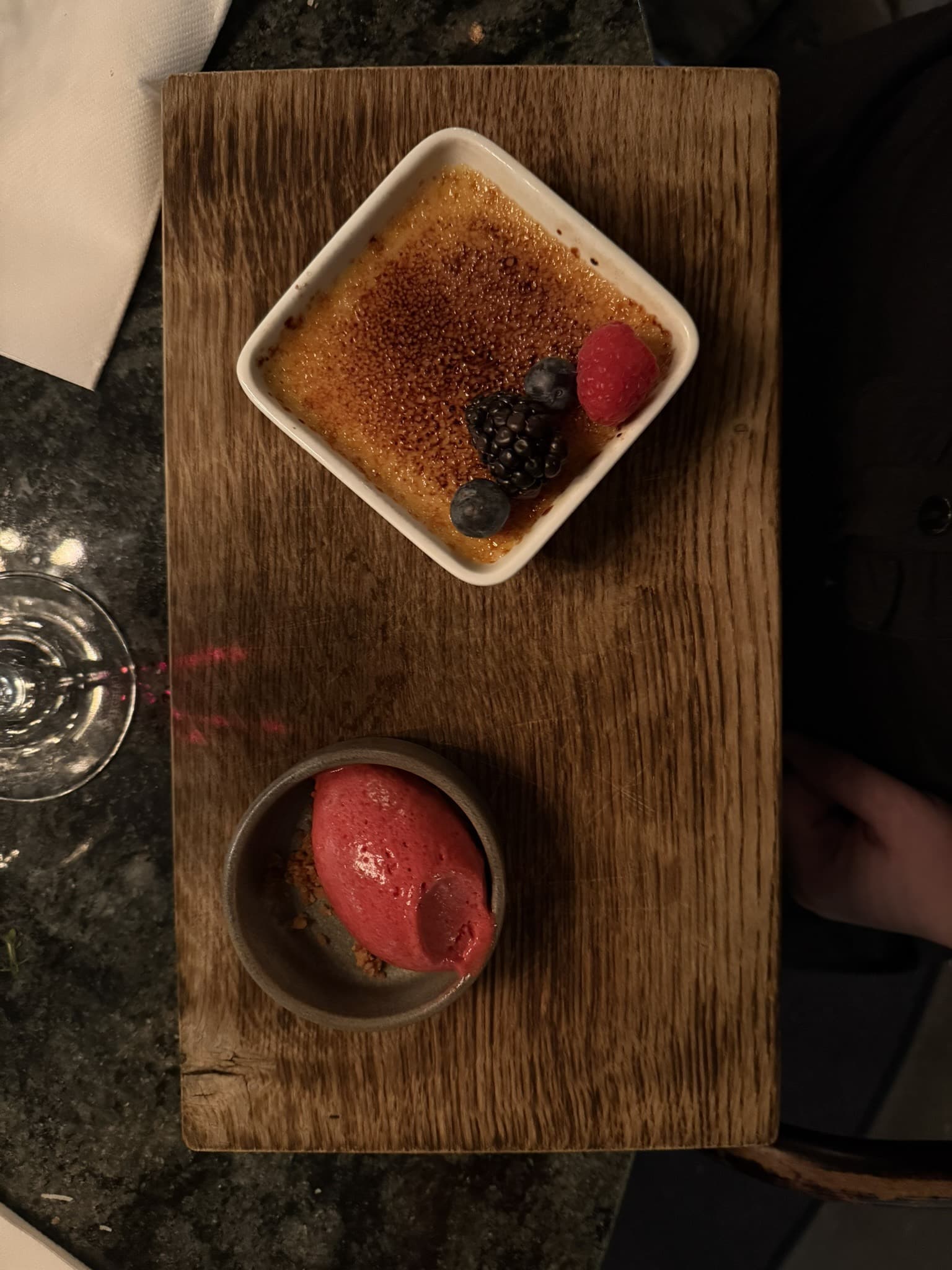 Crème brûlée med bær og rød sorbet på træbræt