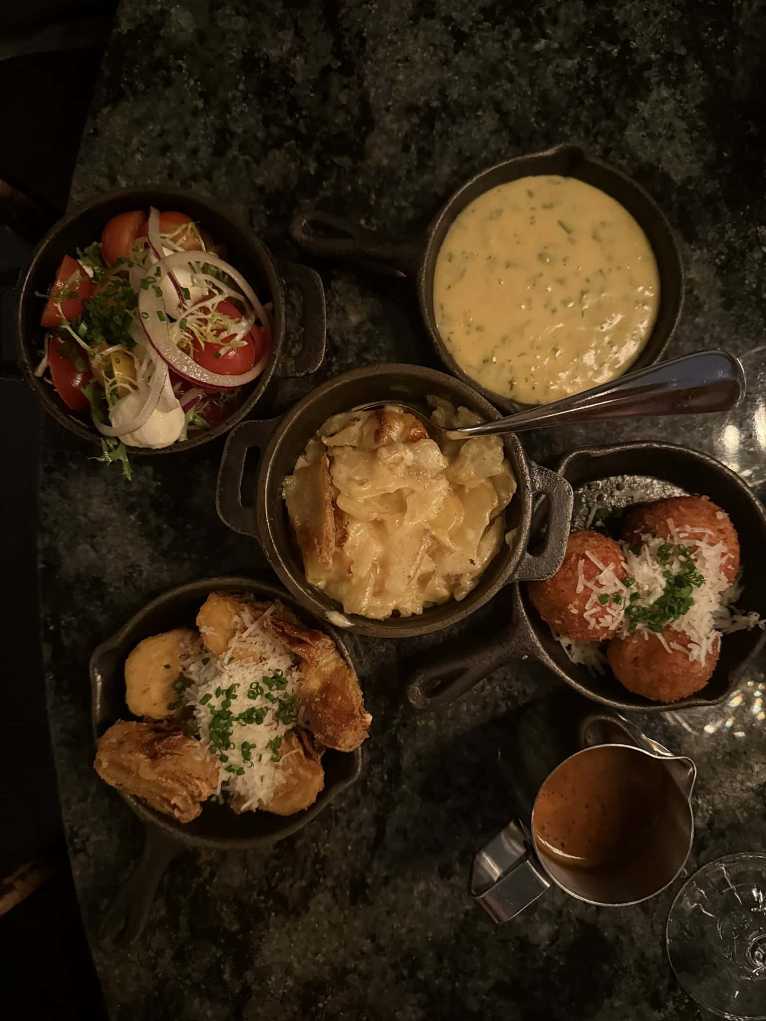 Fem støbejernspander med salat, bearnaise, kartoffelgratin, kroketter og friturestegte artiskokker.