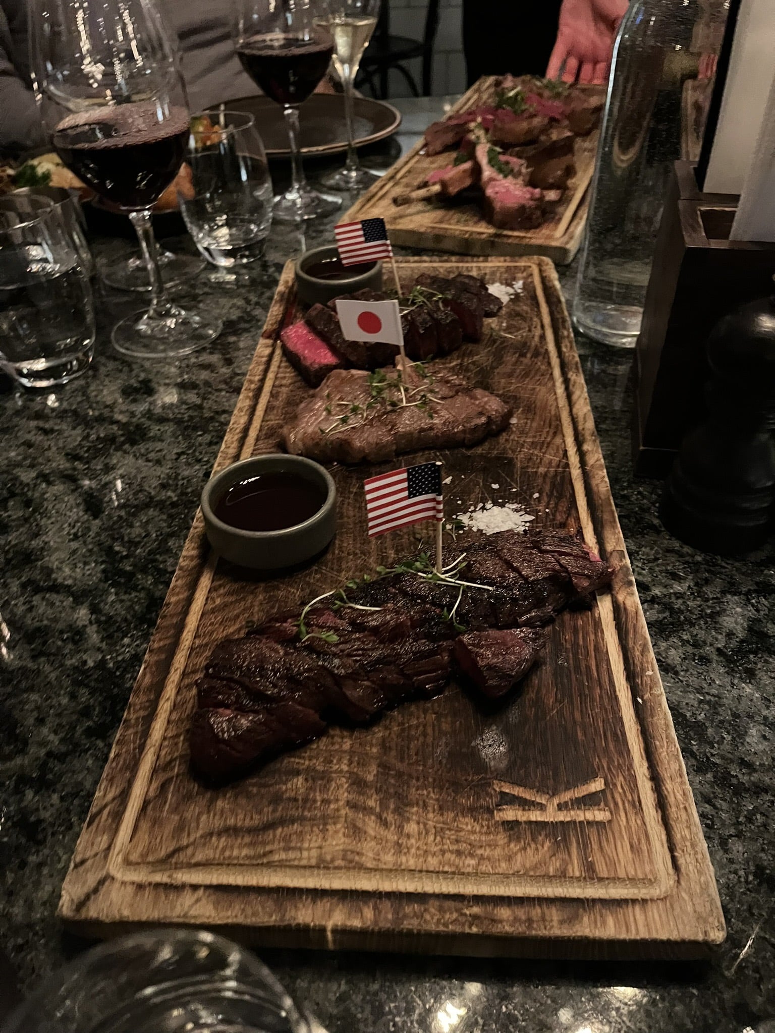 Træbræt med tre udskårne bøffer, små flag, salt og sauce