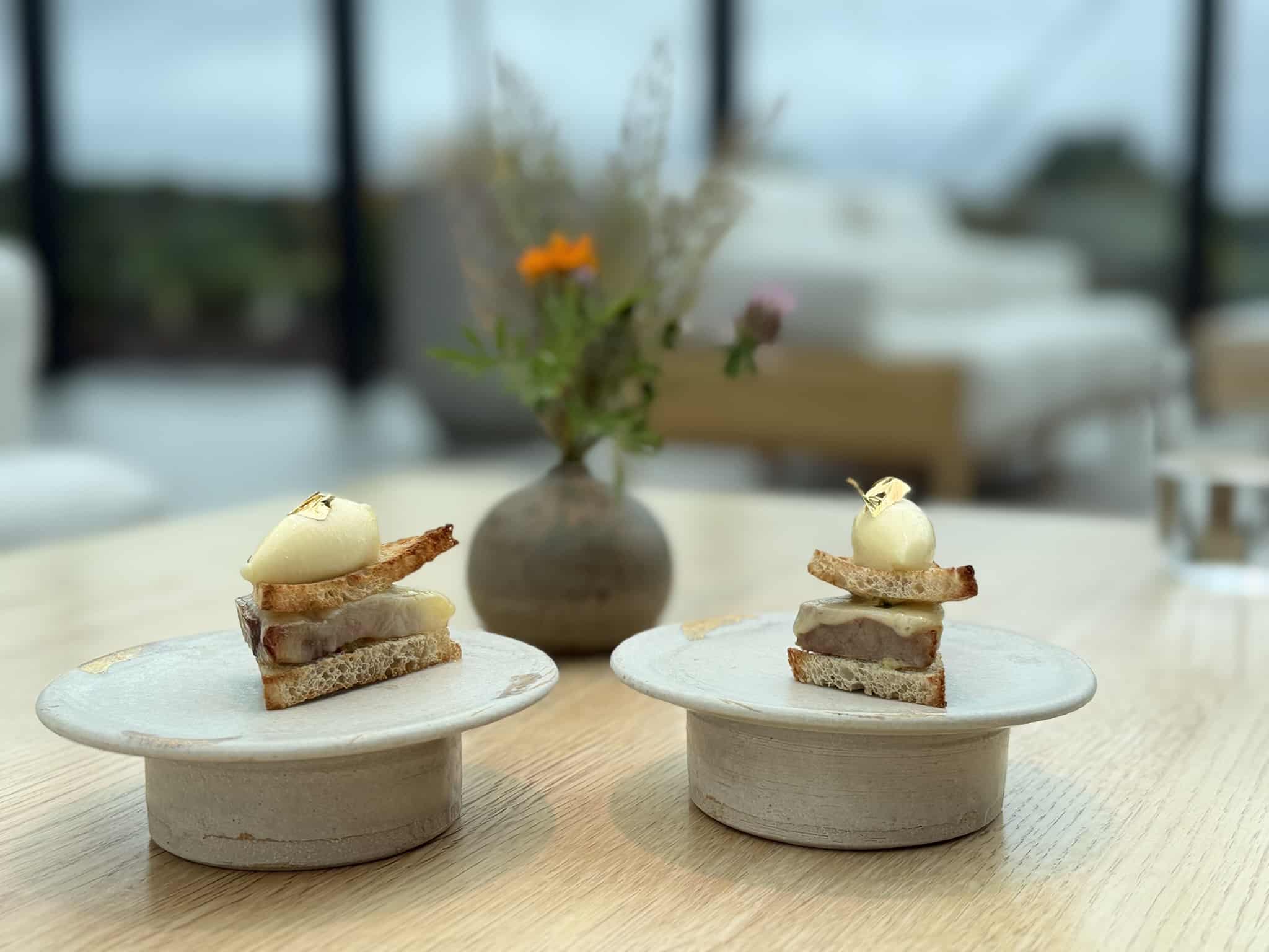 To små sandwich af ristet brød med creme og bladguld på keramikfade