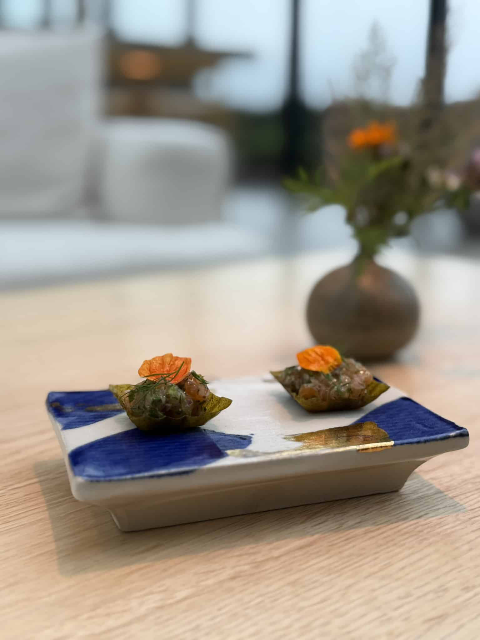 To små sprøde skåle med fisketatar og orange blomsterblad på fad