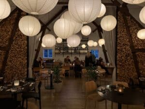 Restaurantsal med rispapirlamper, brændestabler langs væggene og gæster