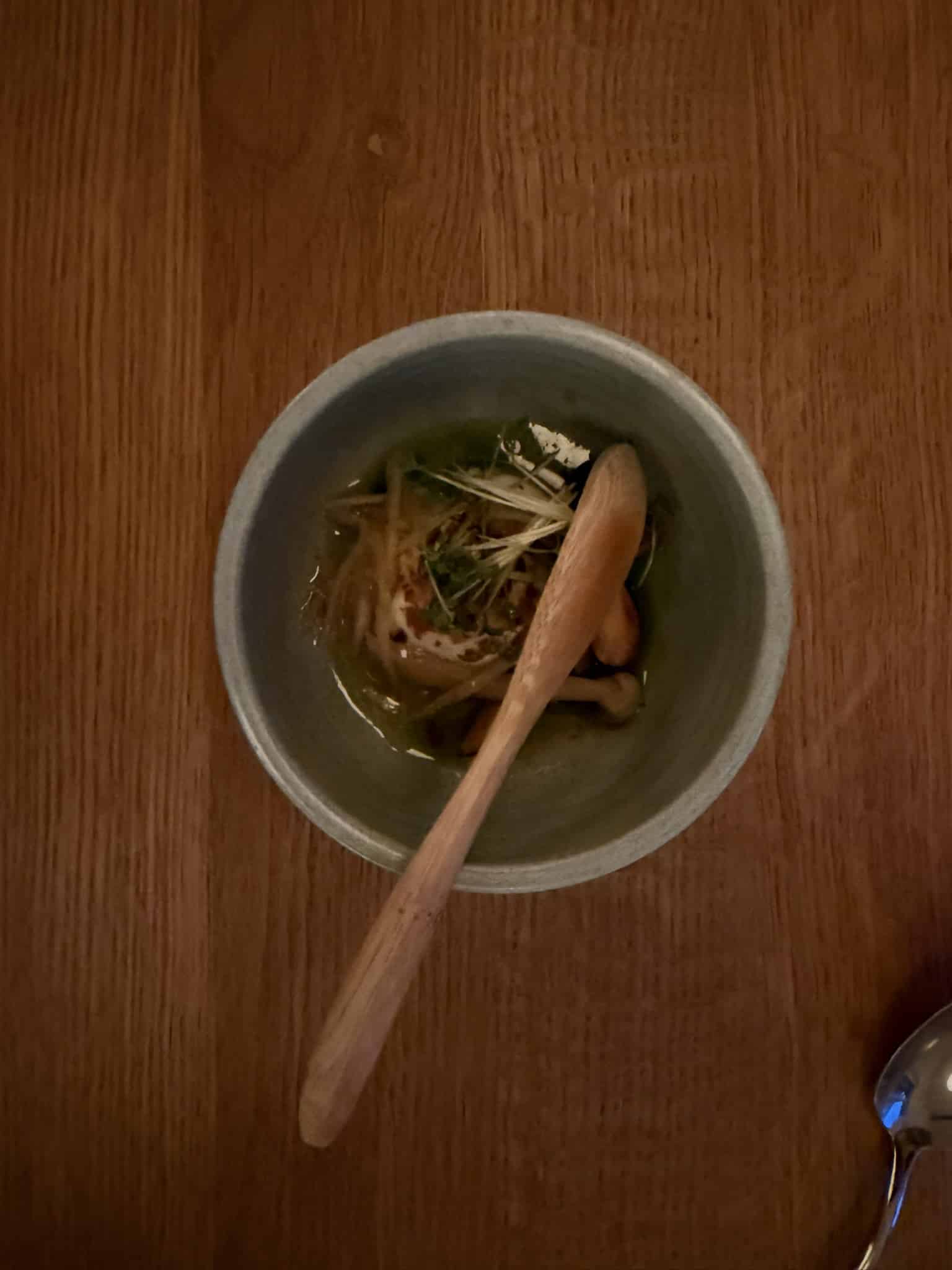 Lille skål med svampe, karse og creme i grøn bouillon