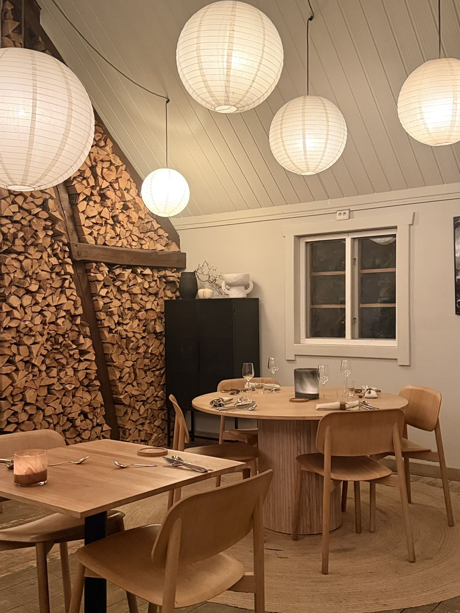 Restaurantlokale med brændestabel, runde papirlamper og træborde med stole