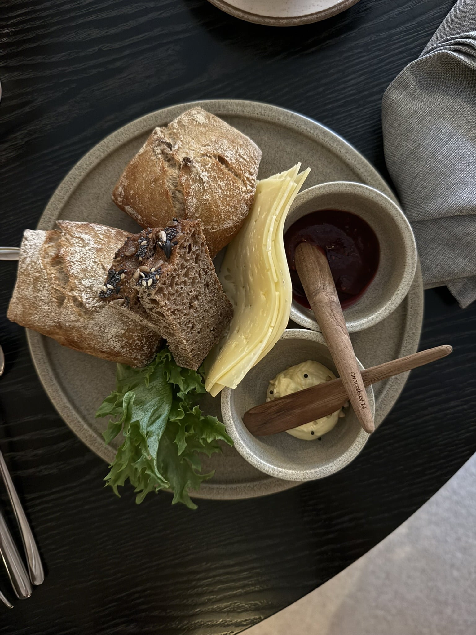 Tallerken med brød, skiveost, salat, marmelade og smør i skåle.