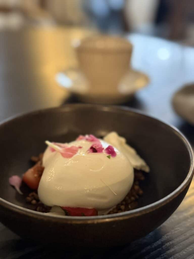 Skål med yoghurt, jordbær, boghvedegranola og spiselige blomster.