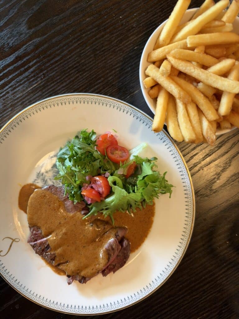 Skiveskåret steak med pebersauce, salat med tomat og skål med pommes frites